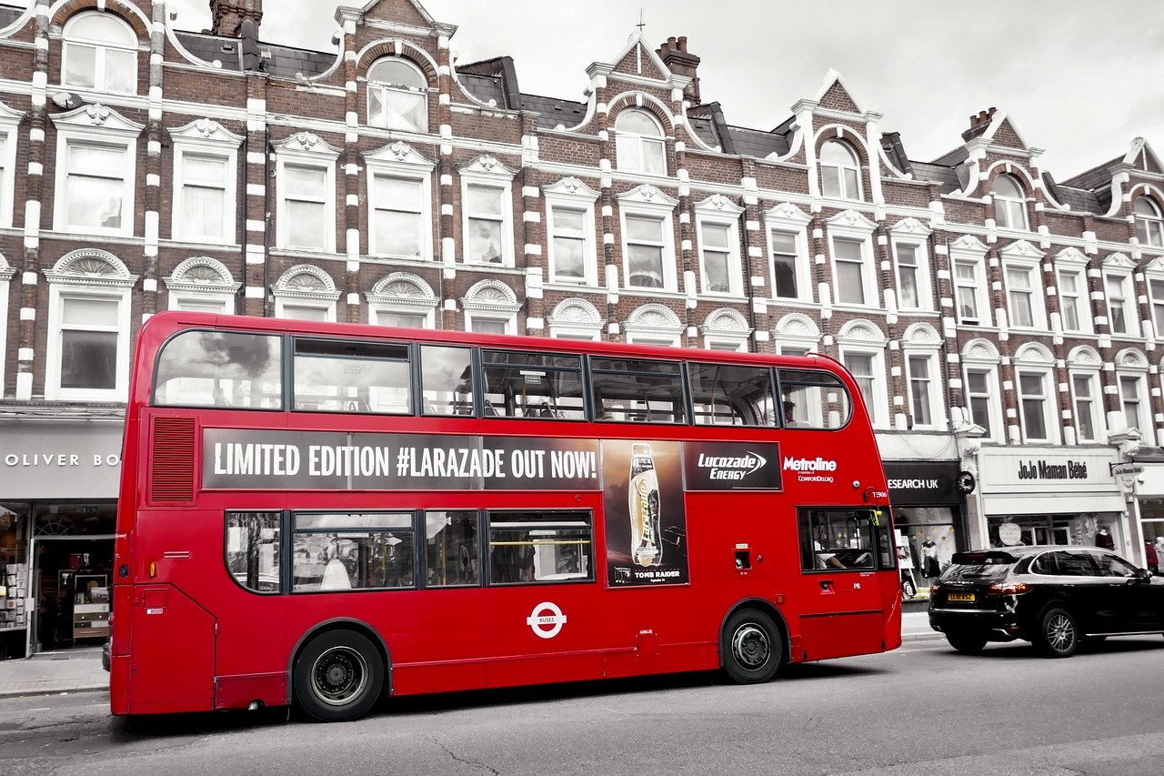 red London bus in front of row of shops with flats above