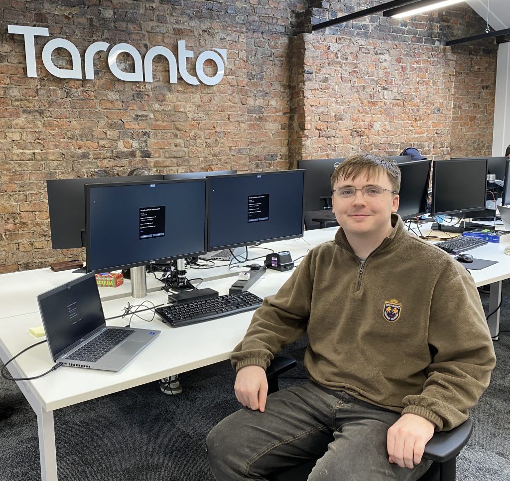 Danny Noctor sitting at a desk with the Taranto logo behind him