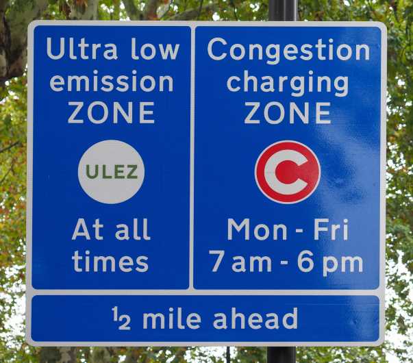 blue road signs indicating 1/2 mile until the ultra low emission zone and congestion charging zone in London