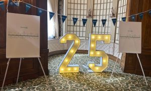 Number 25 in light with blue bunting and notice boards either side of the 25